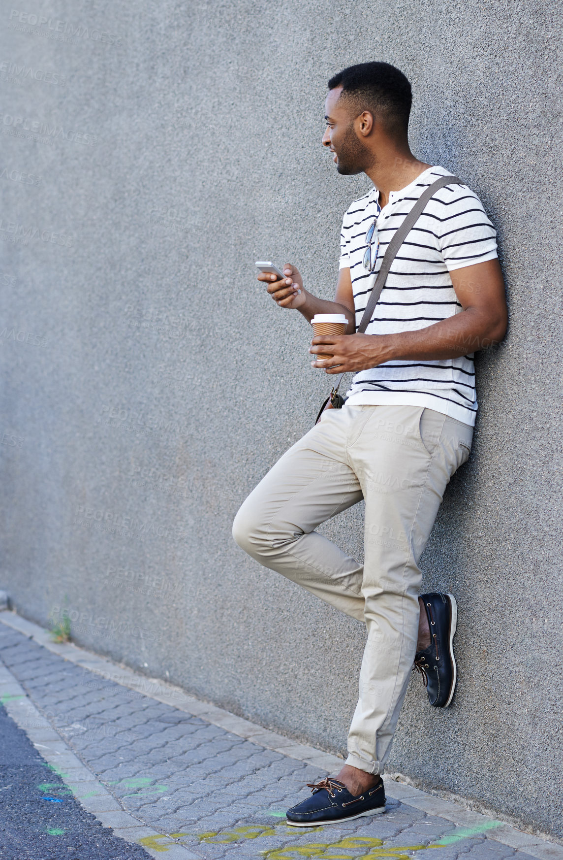 Buy stock photo Black man, coffee and phone in city for texting, social media and scroll online in outdoor. Male person, profile and app for communication in town by wall background, chat and tea on commute or email