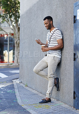 Buy stock photo Black man, coffee and phone in city for email, social media and scroll online in outdoor. Male person, web and app for communication in town by wall, chat and beverage for commute or texting