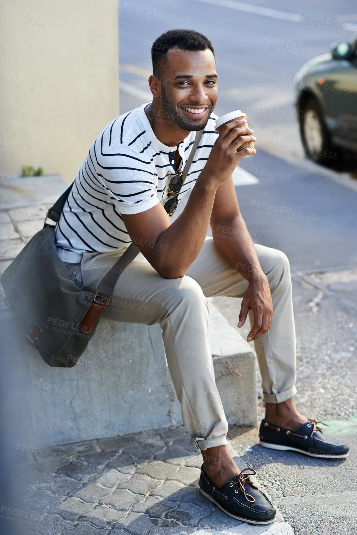 Buy stock photo A handsome casually dressed african american businessman sitting in the city while drinking coffee