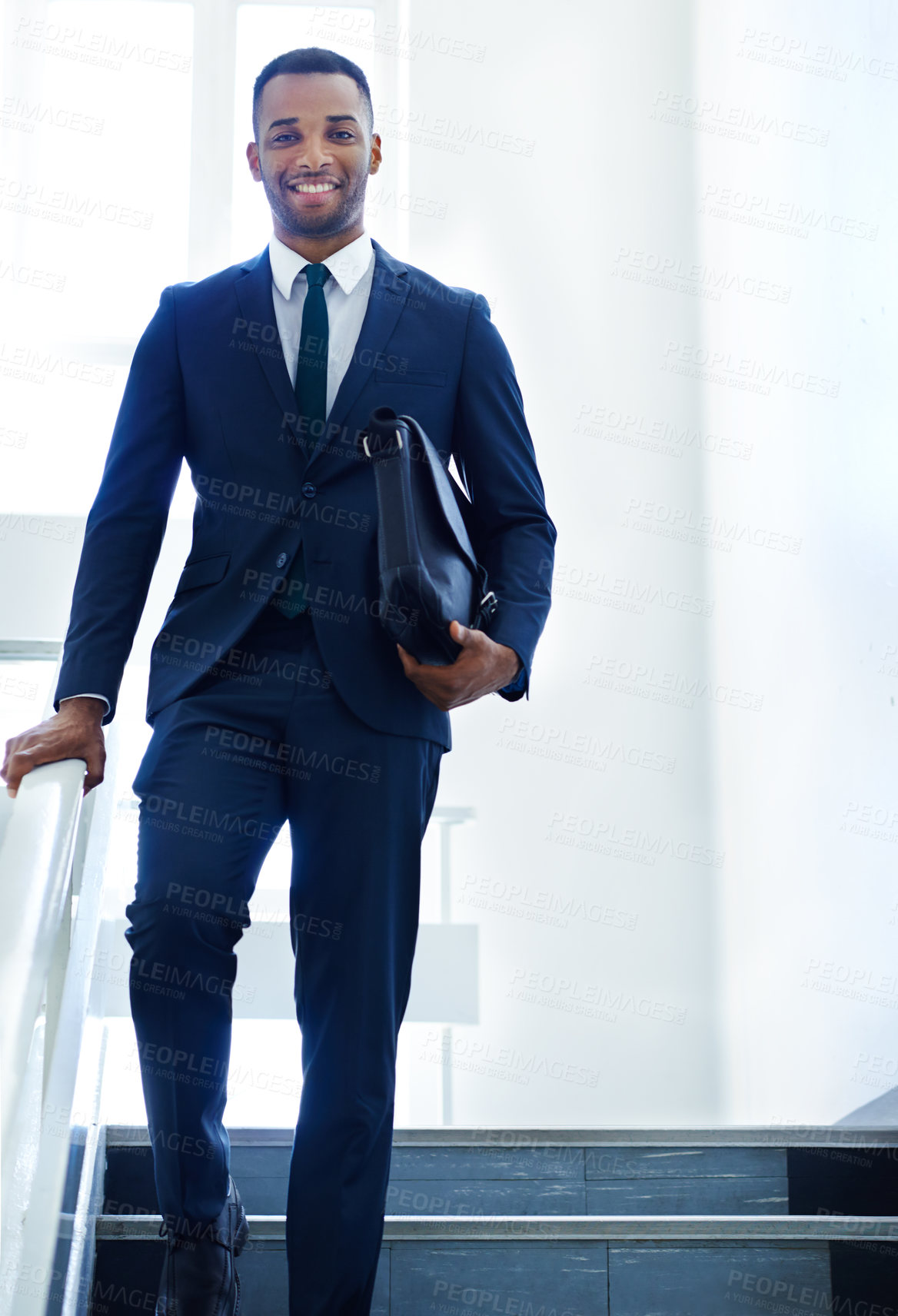 Buy stock photo A handsome young businessman walking while holding his bag