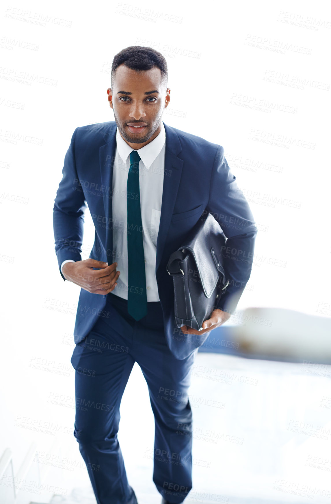 Buy stock photo A handsome african american businessman walking up the stairs while carrying a bag