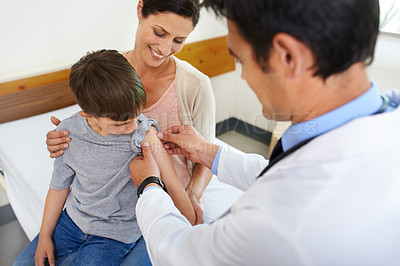 Buy stock photo Shot of a mother watching her son being taken care of by his doctor