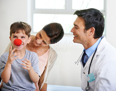 Buy stock photo Shot of a cute young boy playing with a clown's nose in the doctor's room