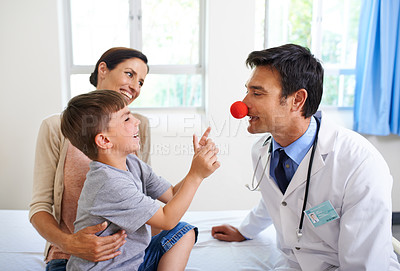 Buy stock photo Shot of a young boy being amused by his doctor
