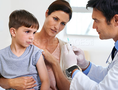 Buy stock photo Shot of a mother and son watching the doctor prepare the needle for an injection