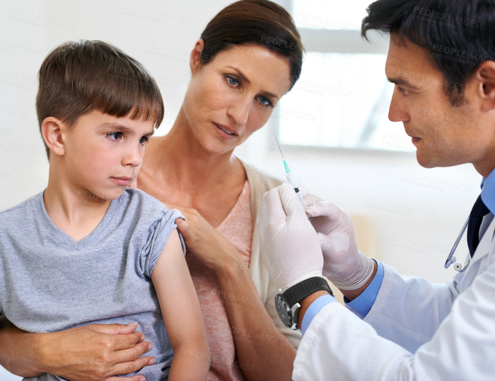 Buy stock photo Shot of a mother and son watching the doctor prepare the needle for an injection