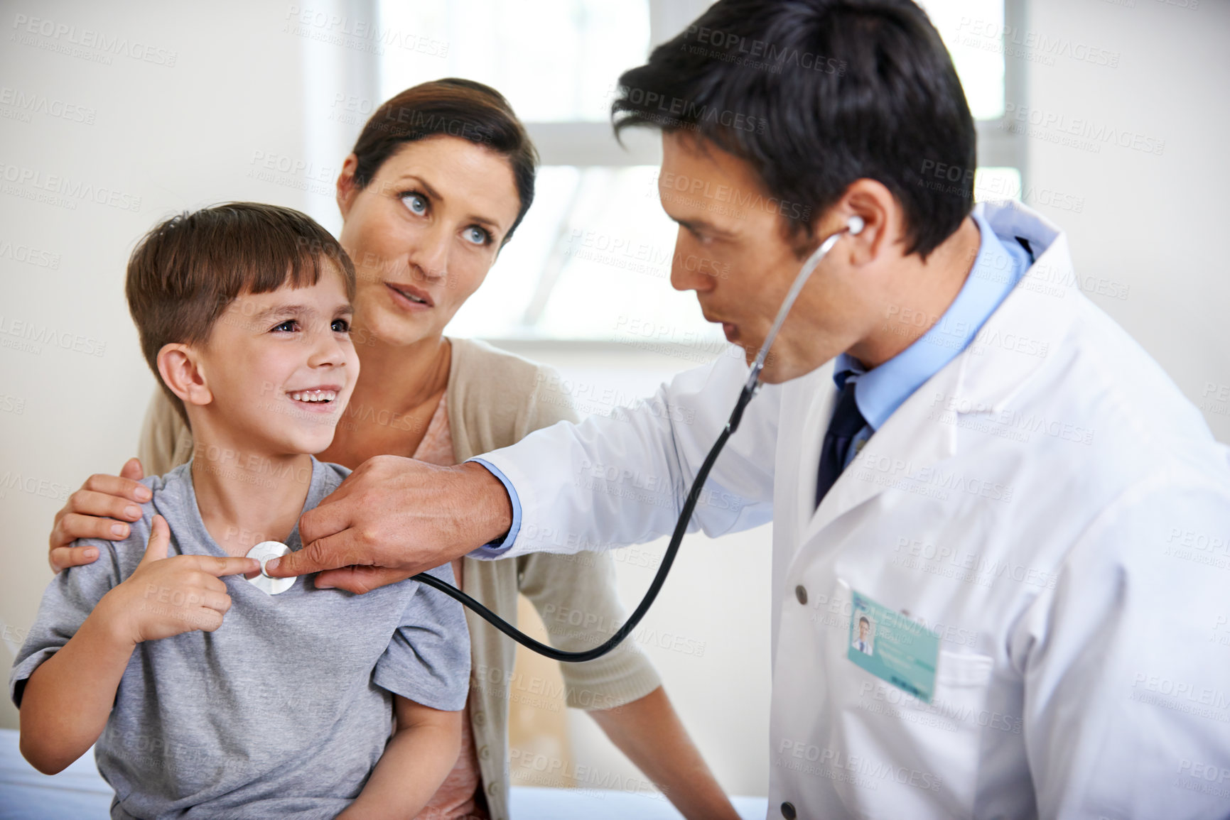 Buy stock photo Indoor shot of a doctor checking a young boy's heart rate