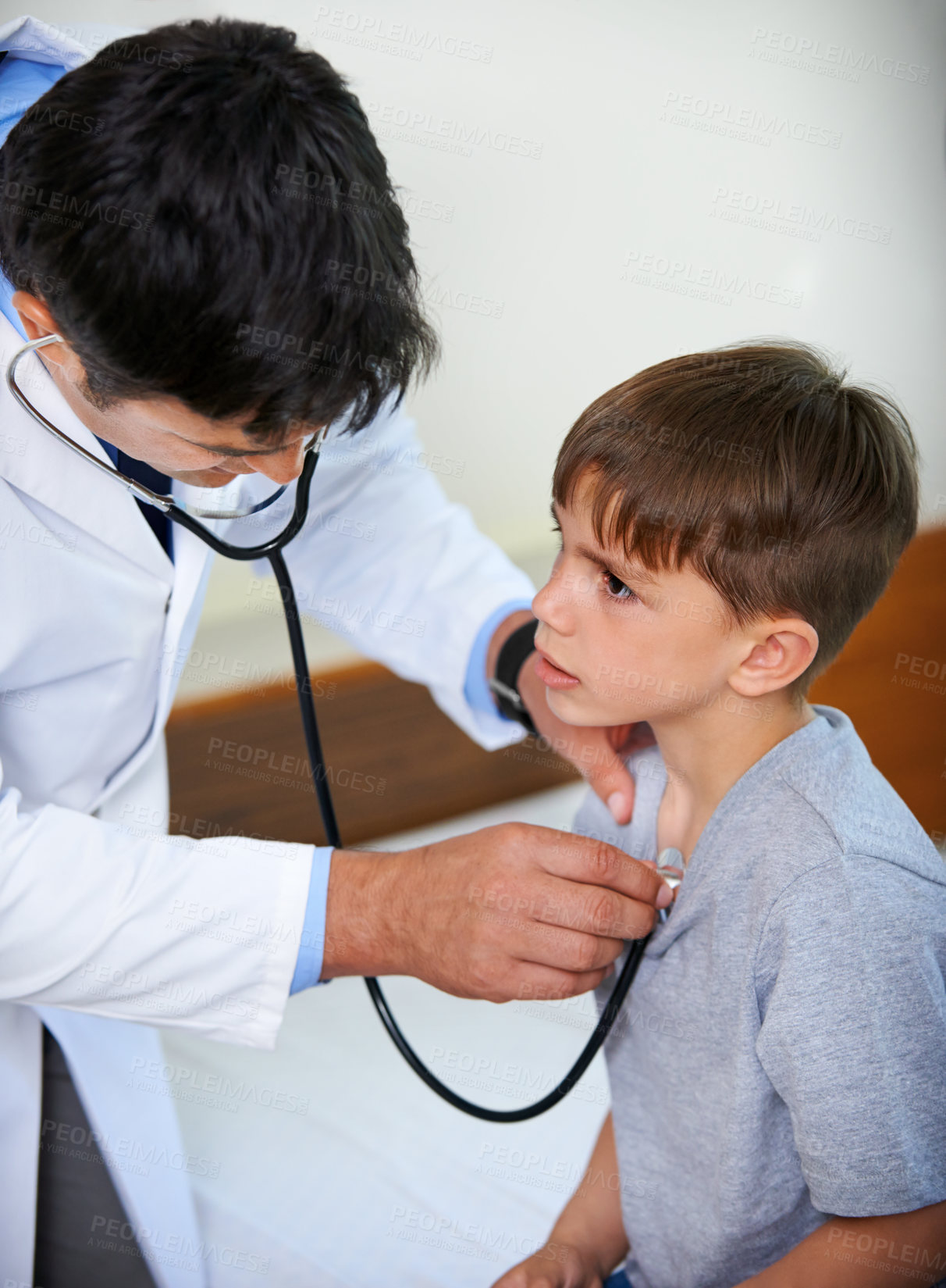 Buy stock photo Shot of a doctor gently examining a young boy with a stethoscope