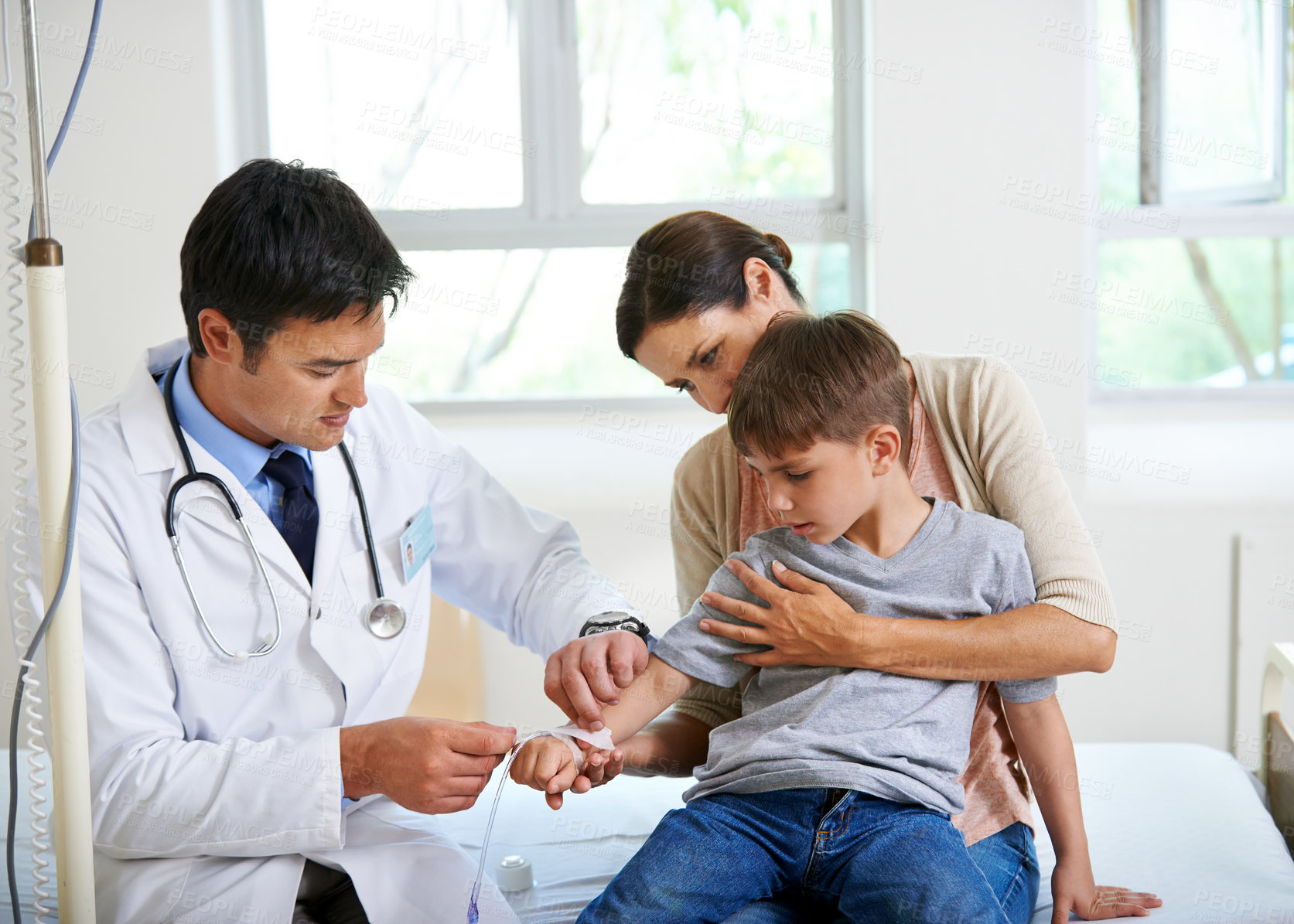 Buy stock photo Shot of a doctor placing an IV in his young patient's hand
