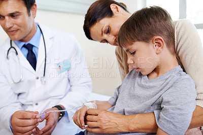 Buy stock photo Shot of a young boy looking down at his IV while his mother holds him tightly