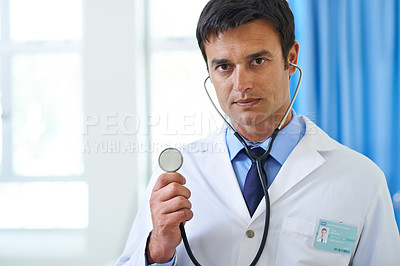 Buy stock photo Portrait of a handsome young doctor looking serious and holding a stethoscope