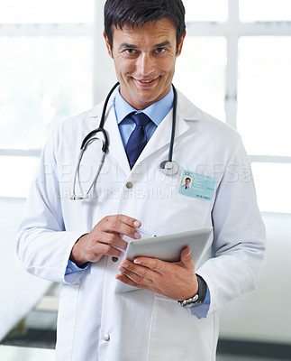 Buy stock photo Portrait of a handsome young doctor using a tablet
