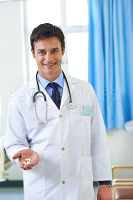 Buy stock photo Portrait of a handsome young doctor holding a pile of pills in his hand