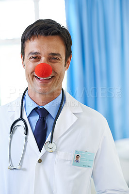 Buy stock photo Portrait of a handsome smiling young doctor wearing a red clown nose