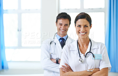 Buy stock photo Portrait of a beautiful young nursing assistant with a young doctor in the background