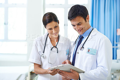 Buy stock photo Shot of a smiling medical team going through a patient's chart