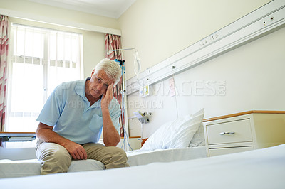 Buy stock photo Portrait of a senior man in pain sitting alone on a bed in a hospital ward