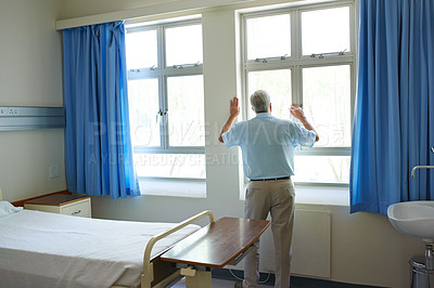 Buy stock photo Shot of a senior man looking out a window while he waits in a hospital ward
