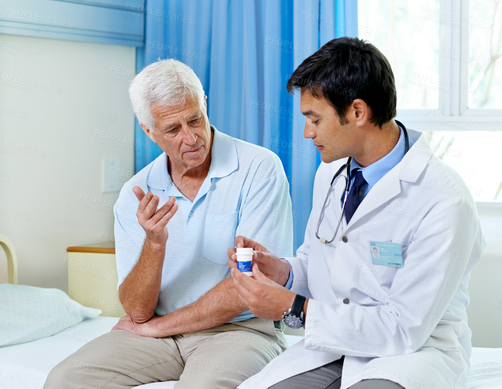 Buy stock photo Shot of a handsome young doctor explaining medication to a senior patient