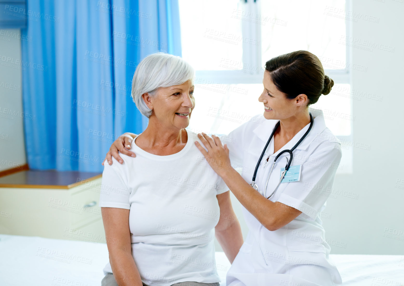 Buy stock photo Happy consultation, nurse and old woman in hospital room for advice, help and support at senior care clinic. Retirement caregiver, counselling and elderly patient with smile on bed with female doctor