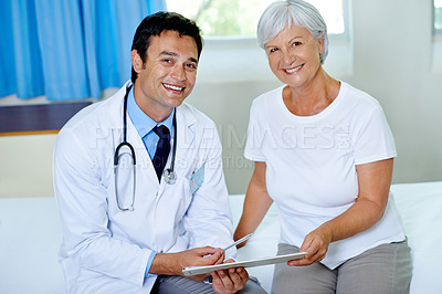 Buy stock photo Portrait of a handsome young doctor going through a chart with a senior patient