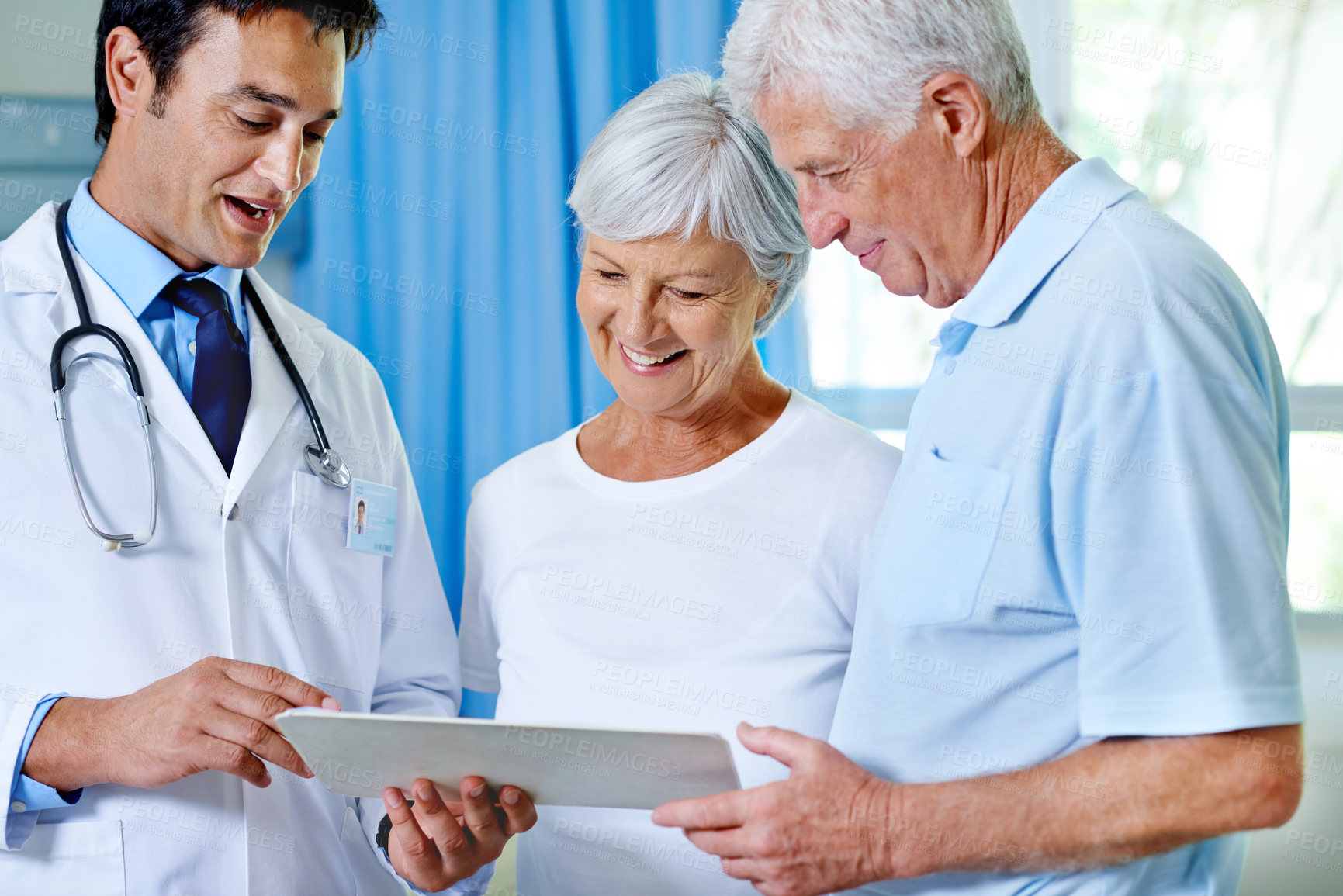 Buy stock photo Shot of a handsome young doctor explaining results to a senior couple