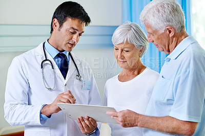 Buy stock photo Shot of a handsome young doctor explaining results to a senior couple