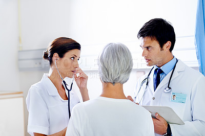 Buy stock photo Shot of two doctors examining a senior patient