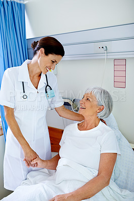 Buy stock photo Shot of a beautiful young doctor comforting her senior patient who is in a hospital bed