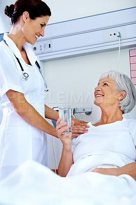 Buy stock photo Shot of a beautiful young doctor attending her senior patient who is in a hospital bed