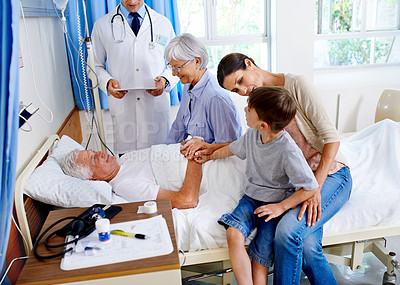 Buy stock photo Shot of a sick man in a hospital bed surrounded by his family