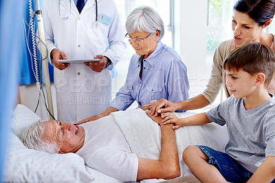 Buy stock photo Shot of a sick man in a hospital bed surrounded by his family