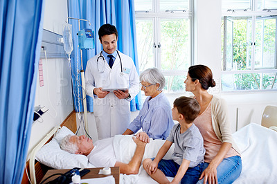 Buy stock photo Shot of a doctor delivering results to a sick man in a hospital bed and his family
