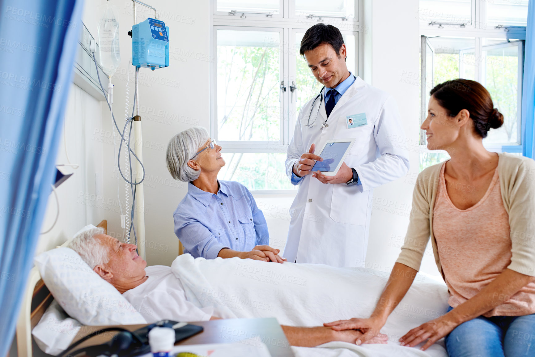 Buy stock photo Shot of a doctor delivering results to a sick man in a hospital bed and his family