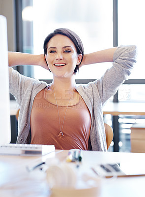 Buy stock photo Shot of a young attractive woman relaxing at her desk in an office