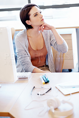 Buy stock photo Shot of an attractive young woman thinking at her desk in an office