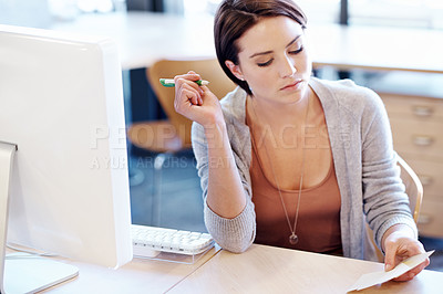 Buy stock photo Shot of an attractive young woman making notes at her desk in an office