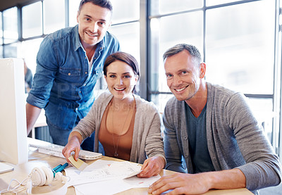 Buy stock photo Shot of three coworkers going through paperwork together