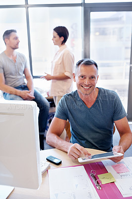 Buy stock photo Portrait of an office worker using a tablet while his coworkers have a discussion in the background