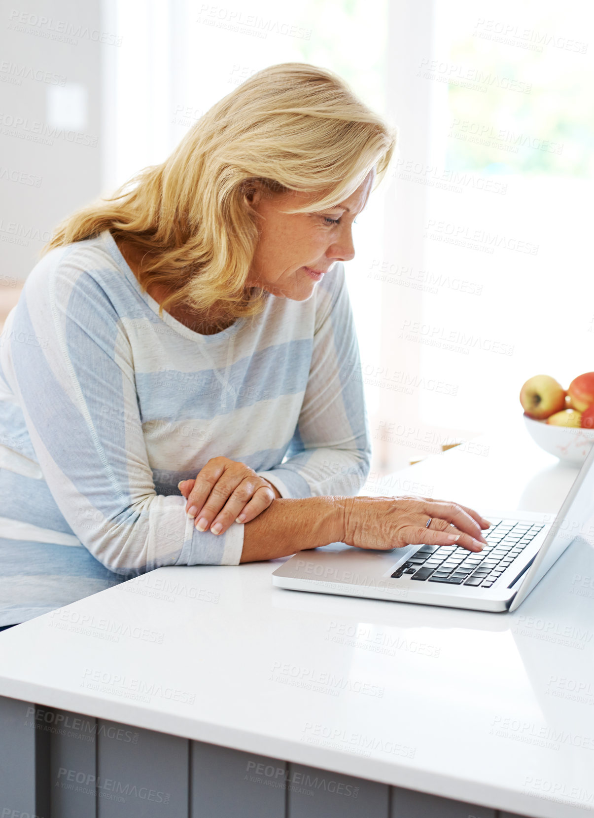 Buy stock photo Laptop, kitchen and typing with senior woman at table in home for browsing internet or research. Computer, remote work and online trading for passive income with elderly person reading in apartment