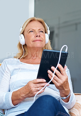 Buy stock photo Shot of a senior woman wearing headphones while holding her digital tablet