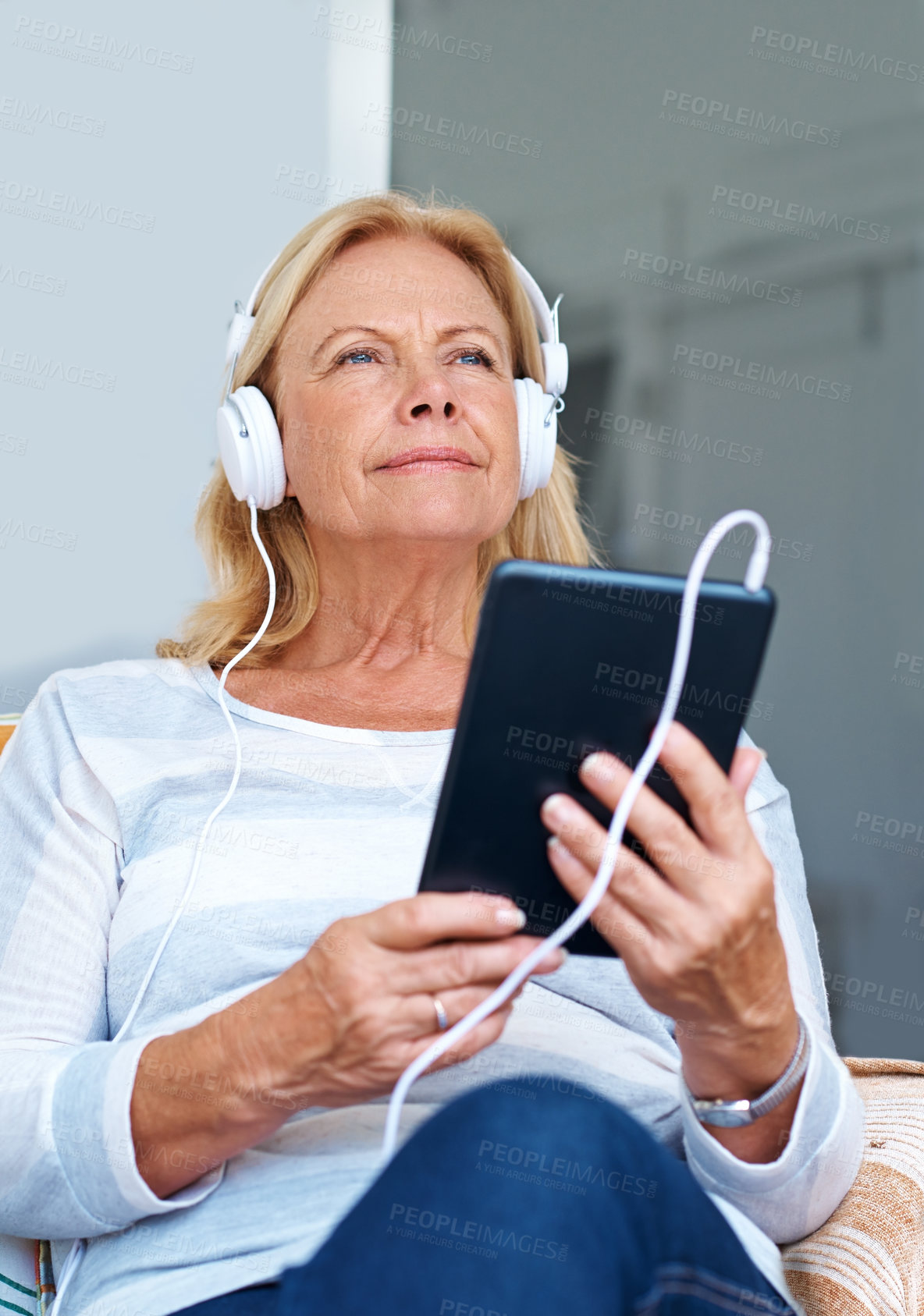 Buy stock photo Shot of a senior woman wearing headphones while holding her digital tablet