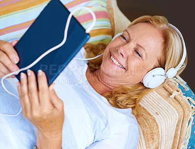 Buy stock photo Shot of a senior woman enjoying herself while looking at the screen and wearing headphones