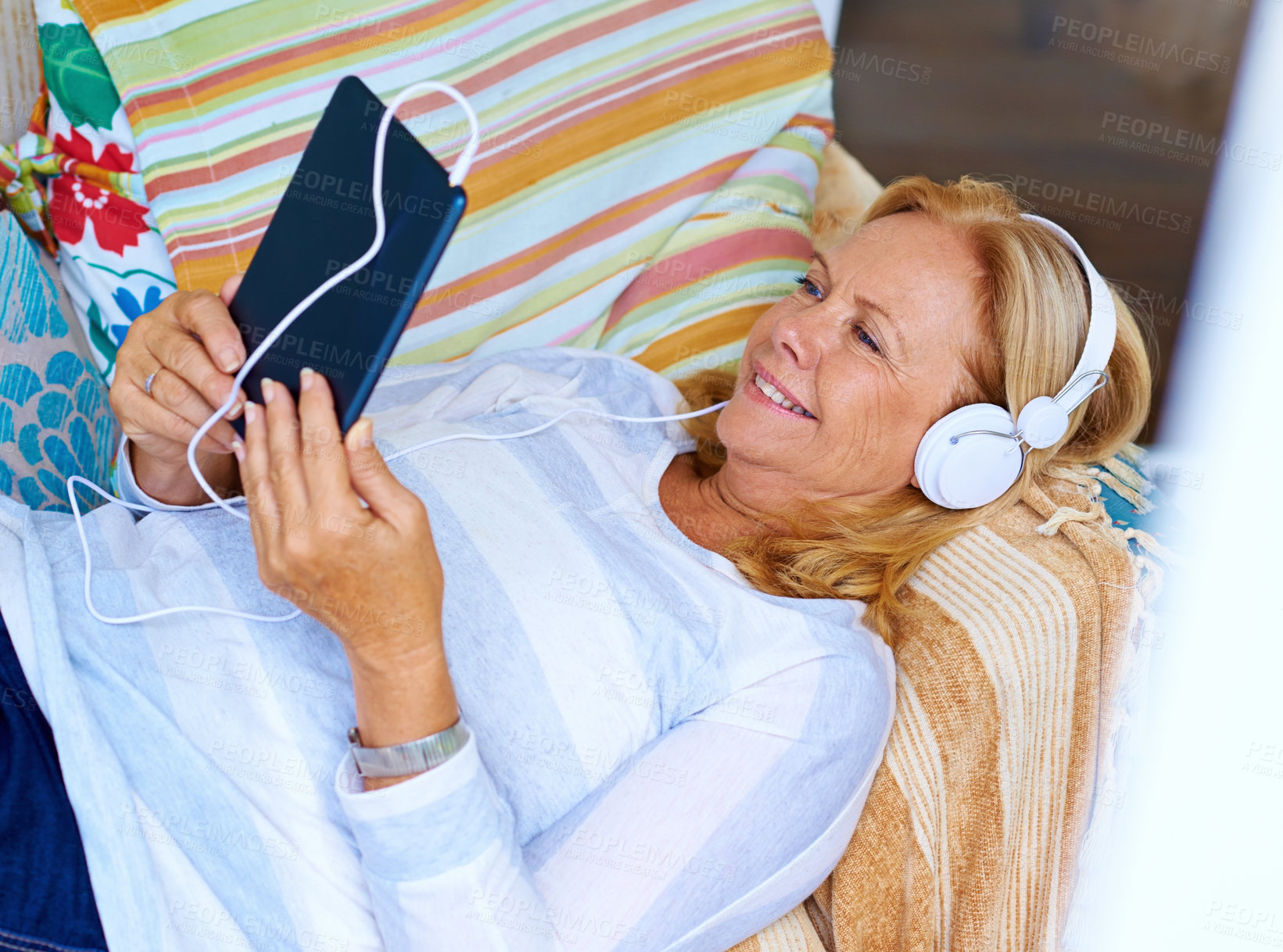 Buy stock photo Tablet, relax and senior woman in patio, happy and headphones for movies, thinking and couch of house. Watch, app and old person with subscription of film, smile and grandma with peace in home