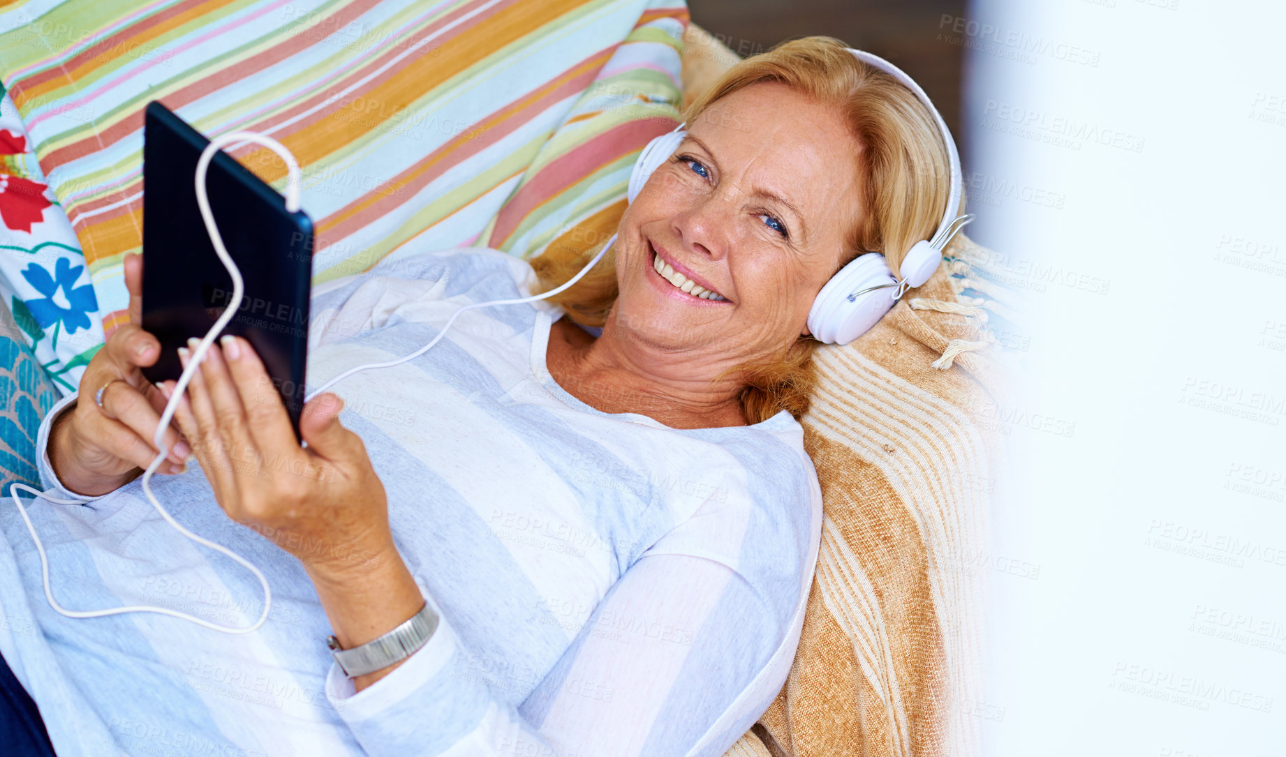 Buy stock photo Senior, woman and portrait with tablet on sofa for relax with music or podcast, happy and playing game. Elderly person, headphones and above on couch in home for reading ebook, streaming and smile.