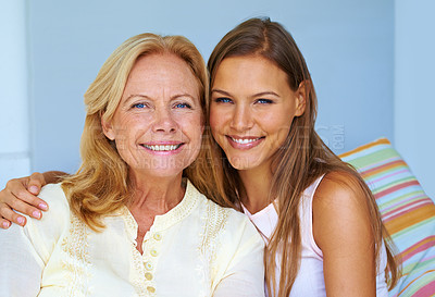 Buy stock photo Portrait of a young woman sitting with her arm around her grandmother