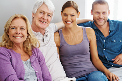 Buy stock photo Shot of a happy family sitting together while smiling at the camera