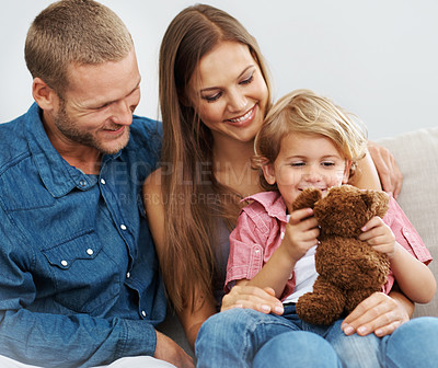 Buy stock photo Shot of a young couple looking at their son as he plays with his toy