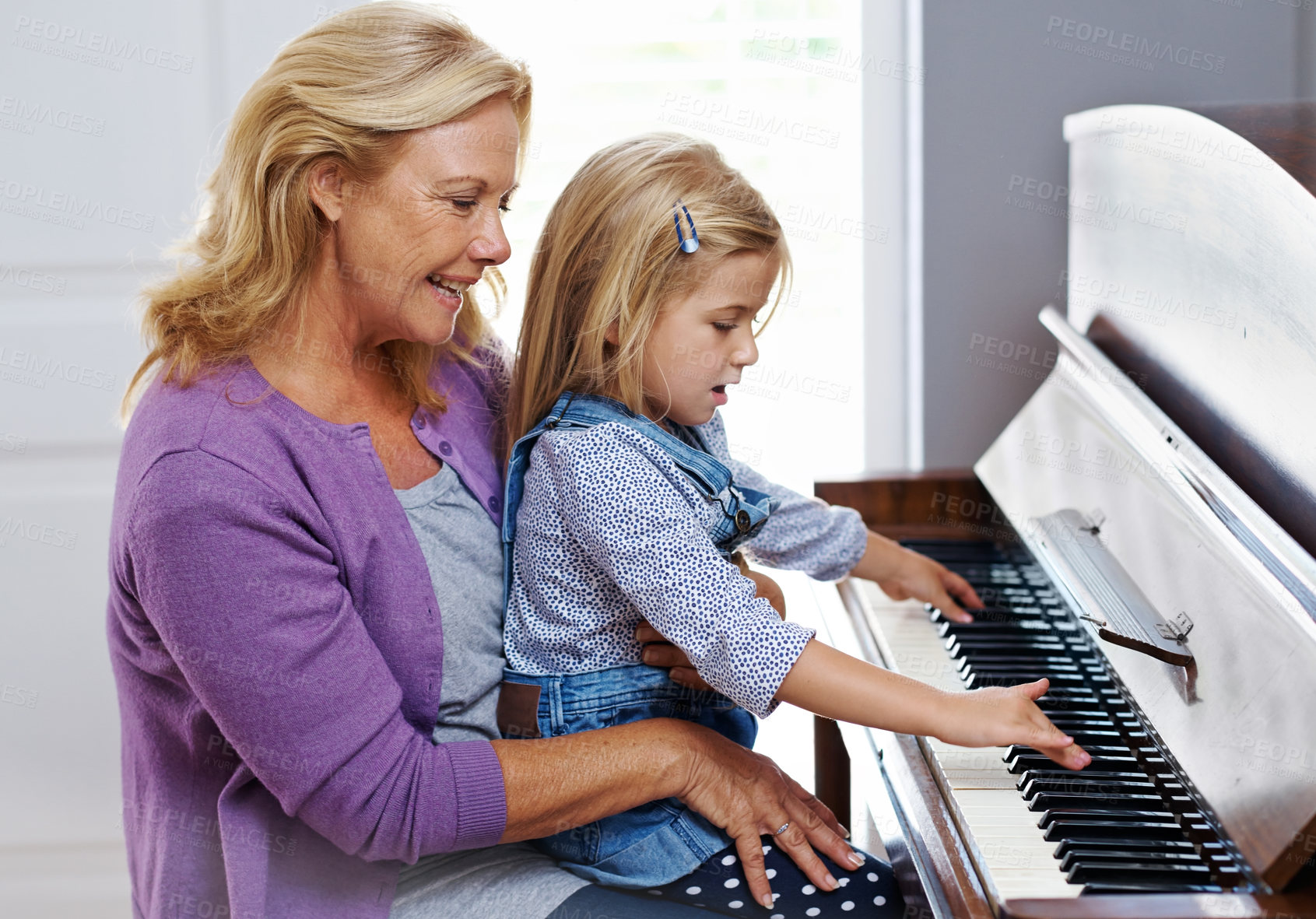 Buy stock photo Cute little girl being taught how to play the piano by her grandmother