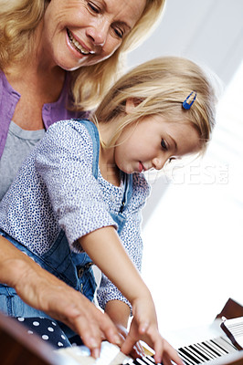 Buy stock photo Shot of a little girl playing piano with her grandmother